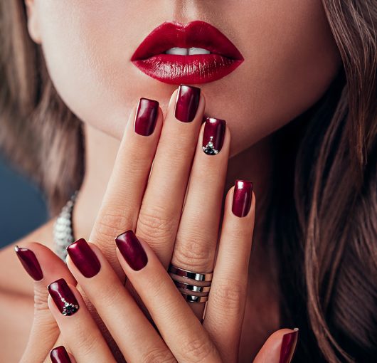 Beautiful woman with red lips and burgundy manicure